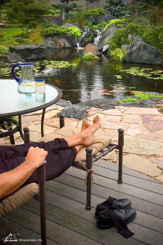 A Man sitting at a table next to a Pond.